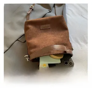 Détail montrant la capacité interne du sac seau en daim marron avec bandoulière en cuir
