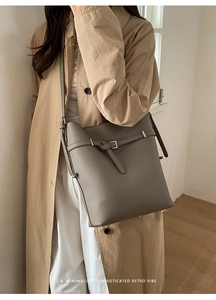 Detailed macro view of gray lychee leather texture and metal buckle on bucket shoulder bag