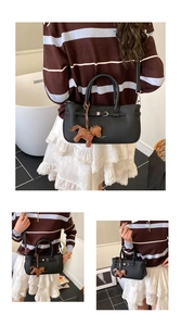 Detail view of black handbag with leather horse charm and fashion buckle strap