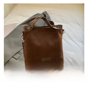 Détail du petit sac carré en daim marron avec boucles argentées et poignée en cuir