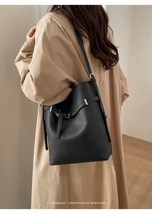 Detail of black lychee grain leather bucket bag with silver buckle worn on shoulder