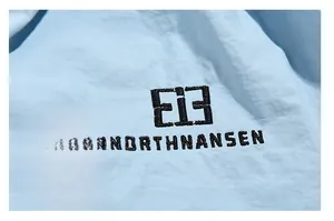 Detail of light blue functional fabric featuring black embroidered E13 Northnansen logo