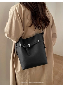Minimalist black pebble leather bucket bag with silver hardware on beige trench coat