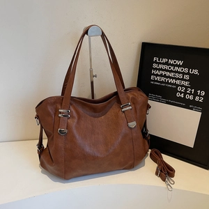 Détail d'un sac cabas en cuir marron avec boucle argentée et bandoulière amovible