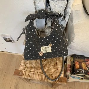Detailed view of gray polka dot handbag with bow decoration and cat patch on a chair