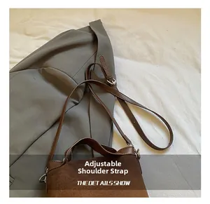Détail de la bandoulière réglable en daim marron avec boucle en métal sur un sac à bandoulière