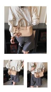 Detail of beige grained leather handbag with brown horse charm and long strap