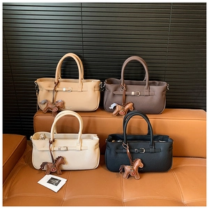 Detail of four colorful tote bags with horse charms and decorative buckles on a leather bench