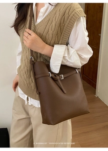 Detailed close-up of dark brown litchi pattern leather and silver buckle on bucket bag