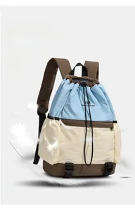 Detail of lightweight drawstring backpack showing color-block nylon fabric and feathers