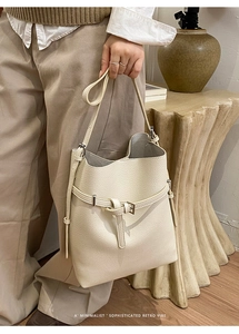 Detail of cream-white lychee grain leather bucket bag with metallic buckle and drawstring