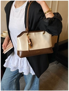 Detail view of cream and brown patchwork tote bag with vintage wood bead pendant