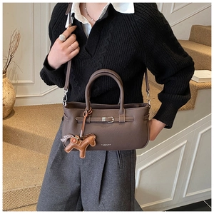 Brown leather handbag with decorative horse pendant and strap detail shown on model