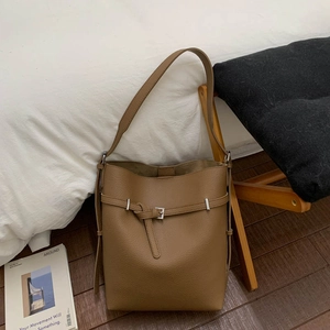 Close-up of brown litchi pattern leather texture and silver buckle on bucket bag