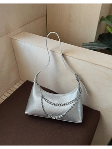 Detailed close-up of metallic silver crossbody bag with double silver chain decoration