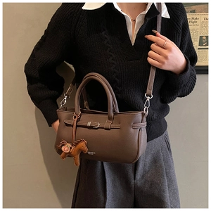 Detailed view of dark brown lychee grain leather handbag with horse charm accessory