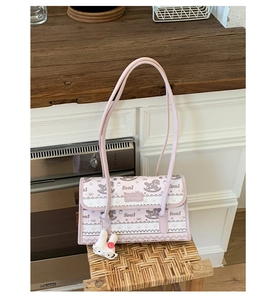 Pink tote bag with horse prints and a cute rabbit charm on a rustic wooden stool