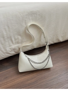 Detailed view of white hobo bag with leather texture and silver chain decoration