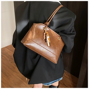 Detail of vintage brown shoulder bag with wax leather texture and wooden bead tassel decor