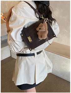Detail of vintage brown square handbag featuring gold twist lock and cute plush bear charm