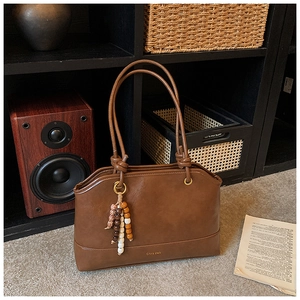 Close-up of retro brown tote bag with beaded tassel detail and round top handles
