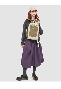 Detail view of stylish beige and khaki oxford fabric backpack with side pockets on model