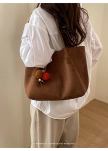 Detail view of a vintage large capacity tote bag with colorful pompom charm on model