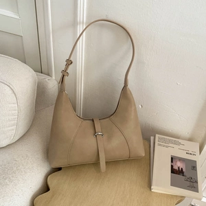 Detail of hobo bag with silver ring buckle and thin strap on a wooden table