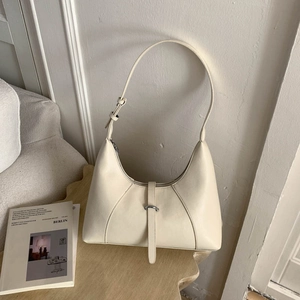 Chic cream semi-circle hobo bag displayed on a wooden table with soft lighting