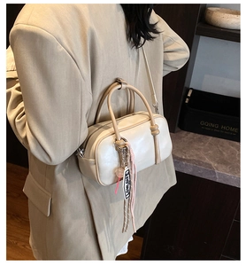 Vue détaillée du sac Boston en cuir crème avec breloque tendance et bandoulière fine