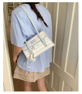 Detail of light blue tote bag with cute plush rabbit charm worn by a model