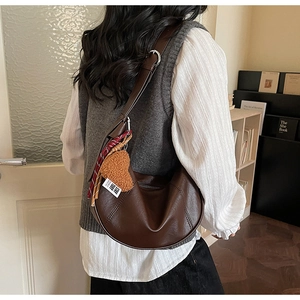 Detailed macro view of dark brown hobo shoulder bag with red tassels and heart charms
