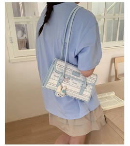 Detail of light blue tote bag featuring foal graphics and a cute rabbit plush charm