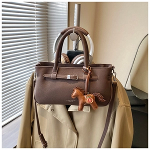 Detail of dark brown lychee textured leather bag with wavy edges and pony charm