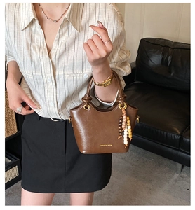 Détail du sac seau en cuir PU marron foncé avec accessoire de franges en perles colorées