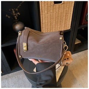 Detail of CHUU dark brown textured leather handbag featuring gold hardware and a cute bear charm