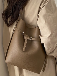 Brown lychee texture leather bucket bag worn with a stylish beige trench coat