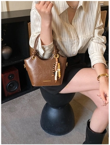 Détail d'un sac à main en cuir marron avec texture litchi et charm en perles de bois