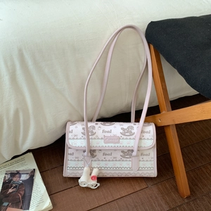 Detail of cute tote bag with horse print, metal brand plaque, and plush rabbit pendant