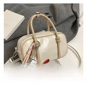 Détail du sac baguette blanc cassé avec anses marron et breloques décoratives de marque