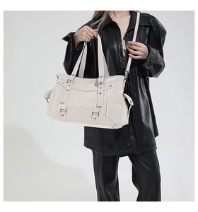 Detail of off-white faux leather tote bag with multi-pocket design and silver hardware