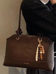 Large capacity vintage brown leather tote bag with beaded tassel charm on grey background