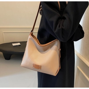Detail of beige pebbled leather hobo bag with slim brown shoulder straps and metal hardware