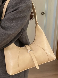 Minimalist beige half-moon shoulder bag in leather shown with a grey wool coat