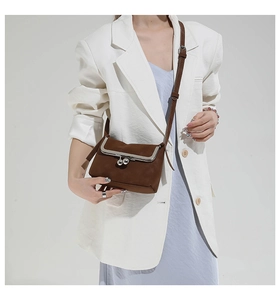 Detailed shot of a brown vintage leather crossbody bag with silver kiss-lock metal frame