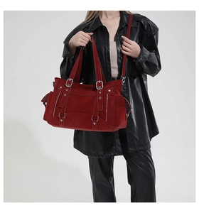Detail of burgundy suede motorcycle tote bag with silver zippers and metal buckle accents