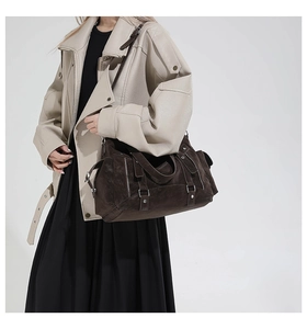 Detail of vintage brown tote with silver zippers and rivets on ivory leather jacket