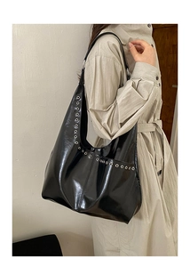 Détail du sac hobo noir brillant avec œillets argentés et intérieur spacieux