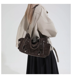 Detailed view of dark brown suede tote bag with metallic zippers and rivet accents