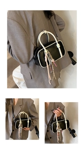 Détail d'un sac baguette noir et blanc avec breloques décoratives et bandoulière